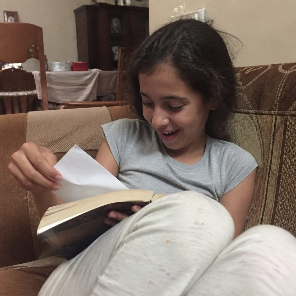 A girl smiling as she finds a Tiny Note tucked inside her book